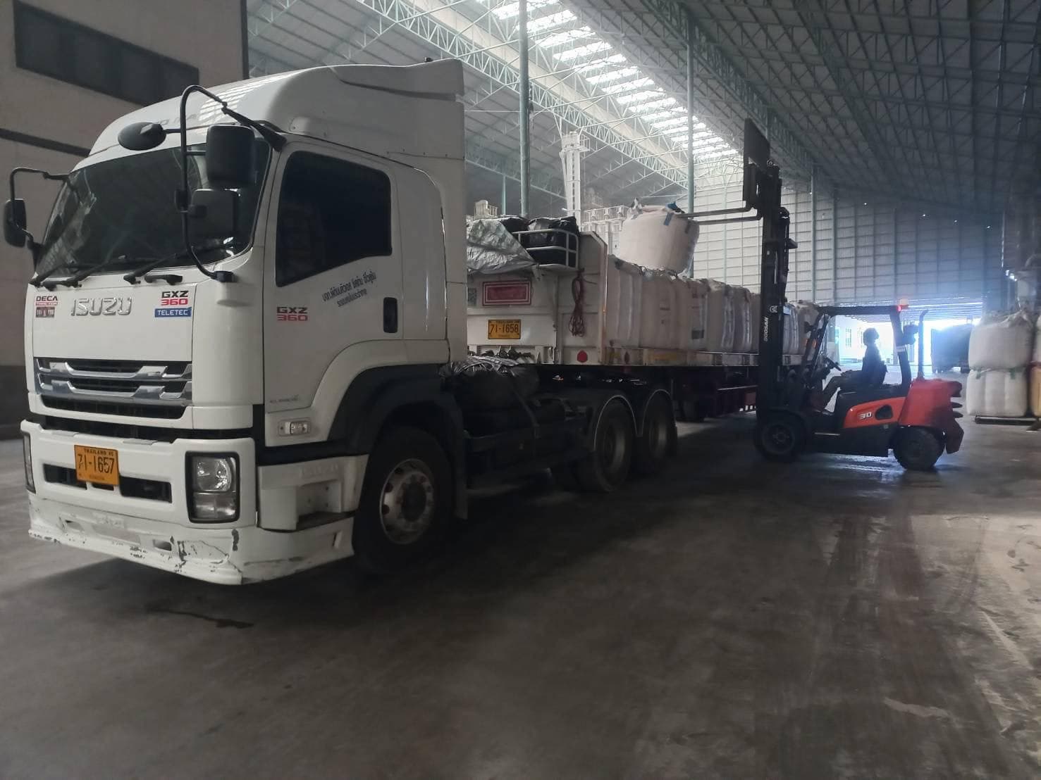 รถหัวลากของ ZCC Express จอดขึ้นของในคลังสินค้า มีรถโฟล์คลิฟต์ยกถุงจัมโบ้ขึ้นรถพ่วง